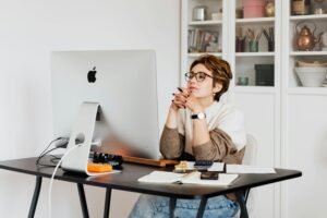 A woman deeply focused on her work at a modern office desk, using a computer.